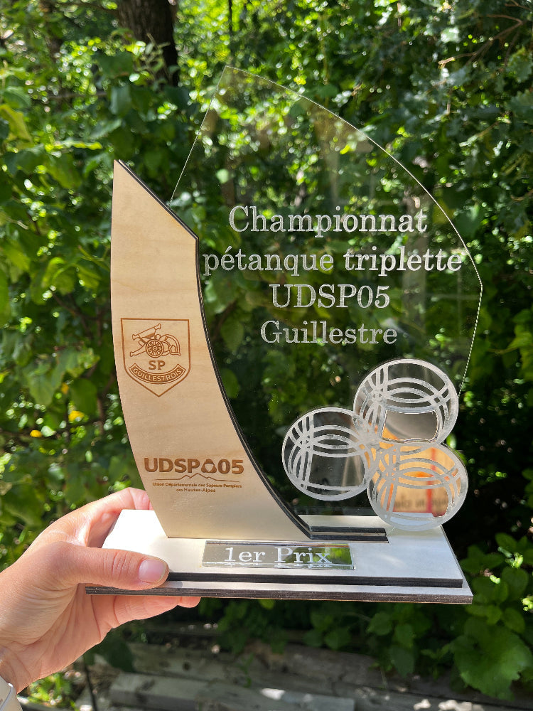 Trophée du championnat de pétanque triplette UDSP05 à Guillestre, en bois et plexiglas, marqué premier prix.
